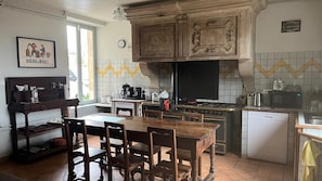 Una cocina con una mesa y sillas de madera, estufa, lavaplatos y refrigerador.