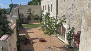 Une cour avec un petit arbre, un banc et une table avec des chaises.