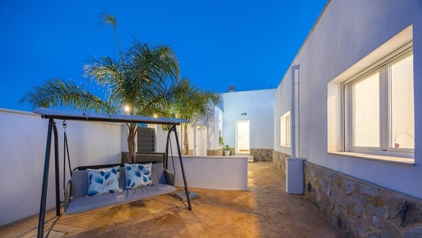 Un patio con una hamaca, un muro de piedra y un edificio con una puerta y ventanas.