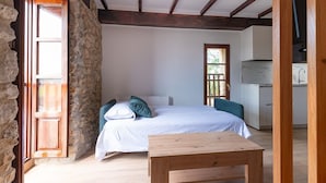A bedroom with a bed, a wooden table, and a stone wall. - Infinity Coast VI by Fidalsa (Miengo)