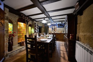 A dining area with a wooden table set for four, a stone wall, and a tiled floor. - Historichaven by Fidalsa (Labastida)