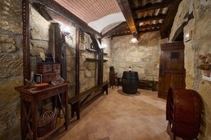 A stone-walled room with a wooden barrel, a bench, and a table with a basket. - Historic Haven by Fidalsa (Labastida)