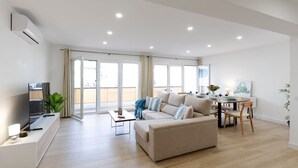 A modern living room with a sofa, TV, dining table, and chairs. - City and Beach by Fidalsa (Alicante)