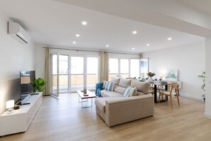 Ein modernes Wohnzimmer mit einer Couch, einem Fernseher, einem Esstisch und Stühlen.