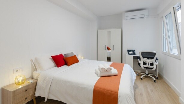 A hotel room with a bed, a desk, a chair, a wardrobe, and an air conditioning unit. - City and Beach by Fidalsa (Alicante)