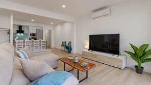 A modern living room with a sofa, a coffee table, a TV, and a potted plant. - City and Beach by Fidalsa (Alicante)