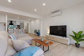 Ein modernes Wohnzimmer mit einer Couch, einem Couchtisch, einem Fernseher und einer Topfpflanze.