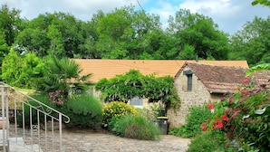 A stone pathway leading to a rustic stone building with a tiled roof, surrounded by lush greenery and flowering plants. - Just 15 minutes from 4 of France's most beautiful villages, the Dordogne valley and the Lot. (Le Pescher)