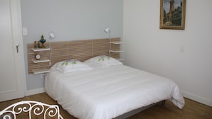 A bedroom with a bed, bedside lamps, a wall-mounted shelf, a door, and a painting. - Just 15 minutes from 4 of France's most beautiful villages, the Dordogne valley and the Lot. (Le Pescher)
