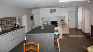 A modern kitchen with a central island, white cabinetry, and a dining area with a sofa and chairs. - Just 15 minutes from 4 of France's most beautiful villages, the Dordogne valley and the Lot. (Le Pescher)