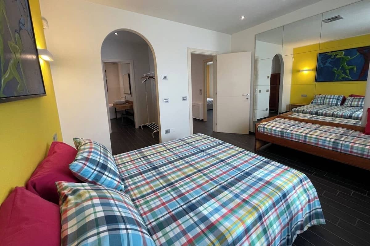 Un dormitorio con cama, espejo y puerta que da a otra habitación.