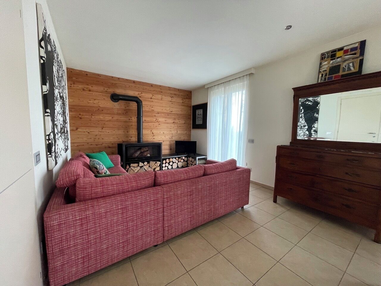 Una sala de estar con un sofá, un panel de pared de madera, una chimenea y un aparador.