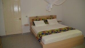 A bedroom with a bed, a door, and a curtain. - Vokundahouse Gambia: Your private home away from home (Serekunda)