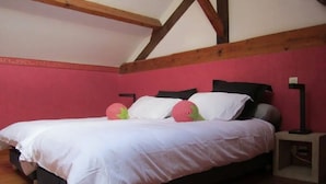 Ein Schlafzimmer mit einem Bett, Holzbalken, einer rosafarbenen Wand und einem Nachttisch.