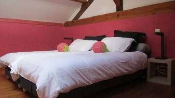 Quarto com cama, vigas de madeira, parede rosa e mesa de cabeceira.