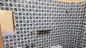 Une salle de bain avec un mur recouvert de carreaux à motifs, un lavabo blanc, des toilettes et une poubelle.