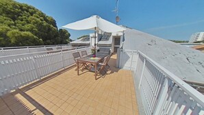 A rooftop terrace with a table and chairs, a white umbrella, and a view of the surrounding area. - Flat with a panoramic terrace and stunning views (Lignano Sabbiadoro)
