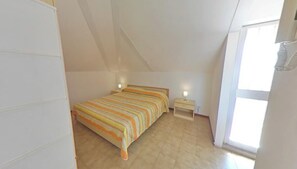 Een slaapkamer met een bed, nachtkastje en een raam.