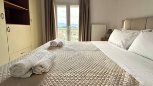 Een hotelkamer met een bed, een kledingkast, een raam met gordijnen en uitzicht op het omliggende landschap.