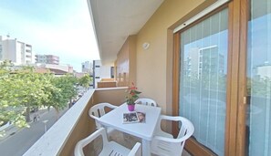 Ein Balkon mit Tisch, Stühlen, einem Blumentopf und einem Fenster mit Jalousien.