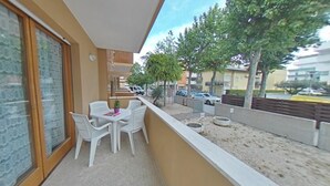 Ein Balkon mit Tisch, Stühlen, einer Topfpflanze und Blick auf die Straße und die Häuser.