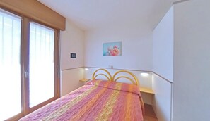 Ein Schlafzimmer mit einem Bett, einem Gemälde und einem Fenster mit Jalousien.