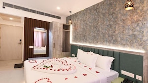 A hotel room with a large bed, a bedside telephone, and a mirror. - Hotel Regency Grande (Thiruvananthapuram)