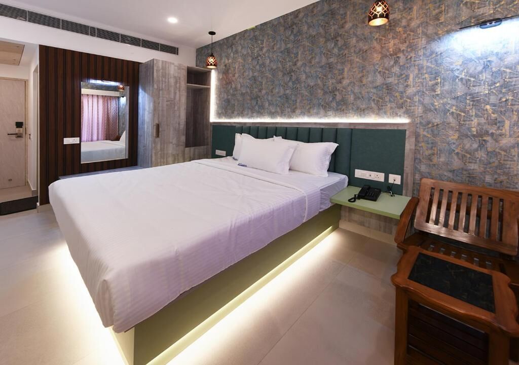 A modern hotel room with a large bed, bedside table, and a mirror.