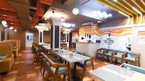 A restaurant with booths and tables, a counter with a menu, and a wall with a quote. - Hotel Regency Grande (Thiruvananthapuram)