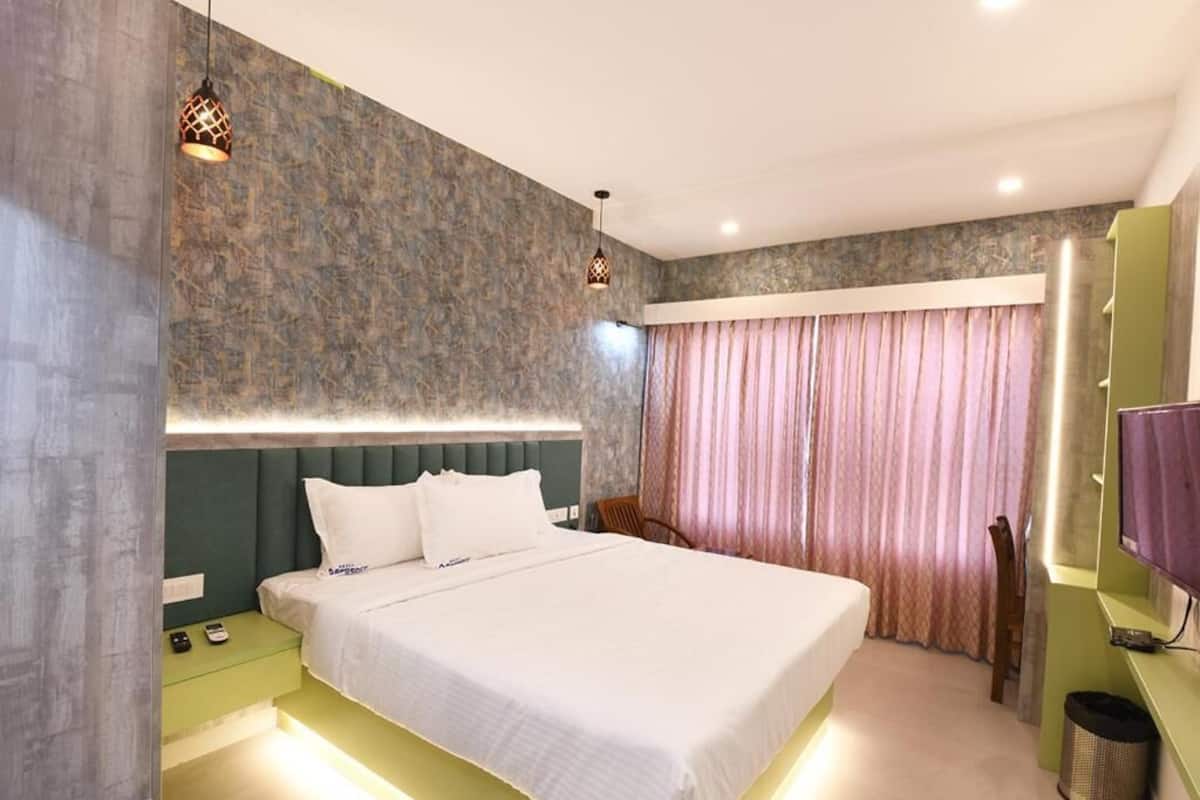 Una habitación de hotel con una cama grande, mesitas de noche, un televisor y una cortina.