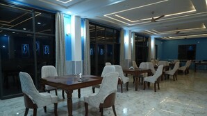 A conference room with a large table and chairs, glass walls, and ceiling lights. - Hotel Griffin (Anandpur Sahib)