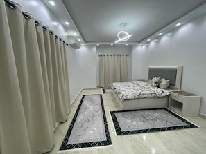 Un dormitorio moderno con cama, mesita de noche y cortinas.