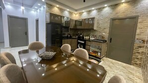 A modern kitchen with a dining area, featuring a wooden table and chairs, a built-in oven, and a stone wall backsplash. - La Dolce Villa with Private Pool (Alexandria Governorate)