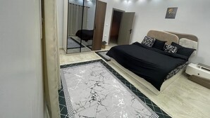 A bedroom with a bed, a nightstand, a mirror, and a door. - La Dolce Villa with Private Pool (Alexandria Governorate)