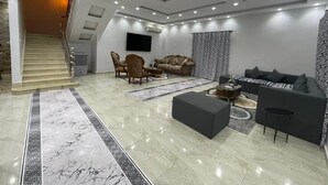 A spacious living area with a staircase, a flat-screen TV, and a sofa set. - La Dolce Villa with Private Pool (Alexandria Governorate)