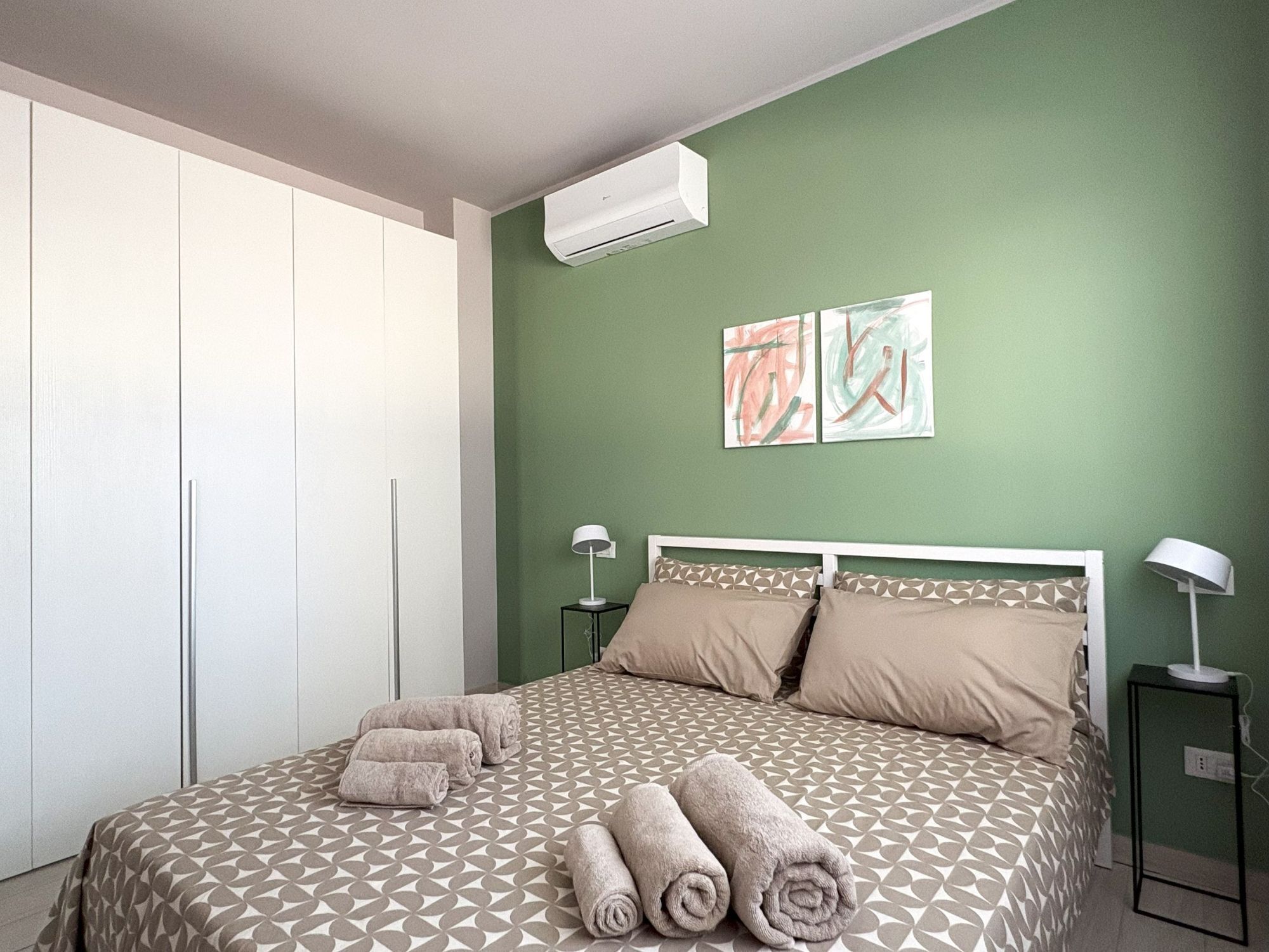 Ein Schlafzimmer mit einem Bett, zwei Nachttischen, einer Klimaanlage und einem Kleiderschrank.
