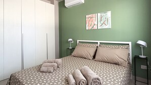 Une chambre à coucher comprenant un lit, deux tables de chevet, un appareil de climatisation et une armoire.