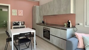 Une cuisine compacte avec un coin repas, un four encastré et une machine à café.