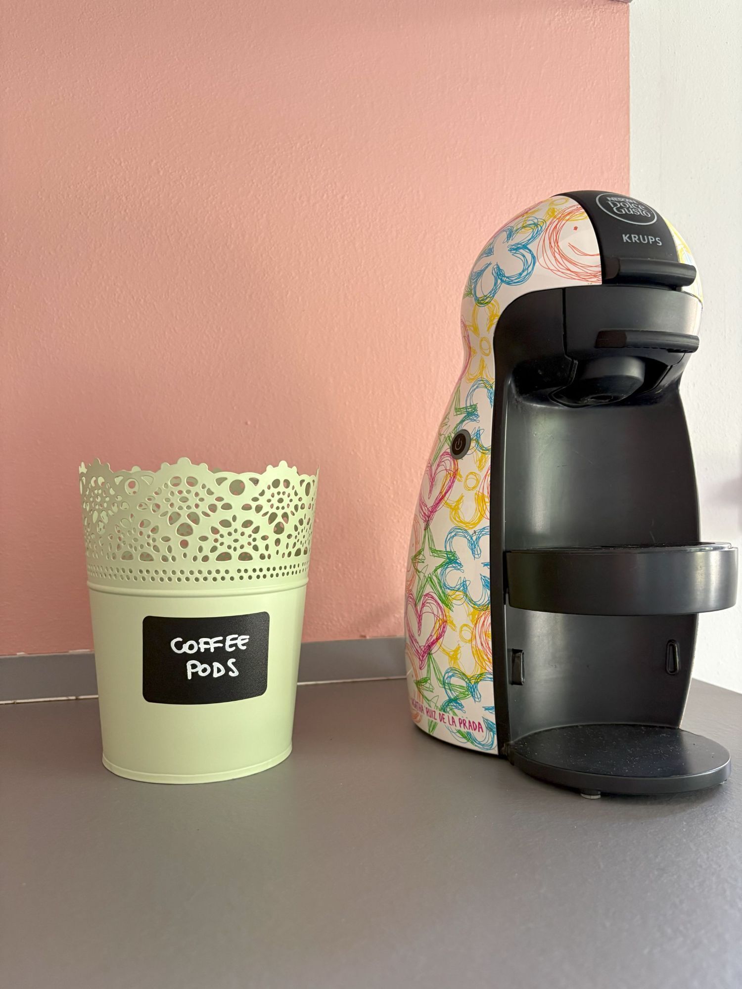 Une machine à café et un support à dosettes de café sont posés sur une table.