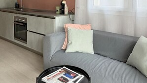 Une cuisine moderne dotée d’un four encastré et d’un canapé gris agrémenté d’un coussin.