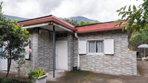 A stone building with a red roof, a white door, and shutters. - La Kaz Montagne Authentique, 6 pers. Mountain view, with Creole garden (Cilaos)