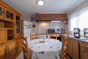 Una cocina con armarios de madera, una mesa de comedor con sillas, un refrigerador, una estufa y un microondas.
