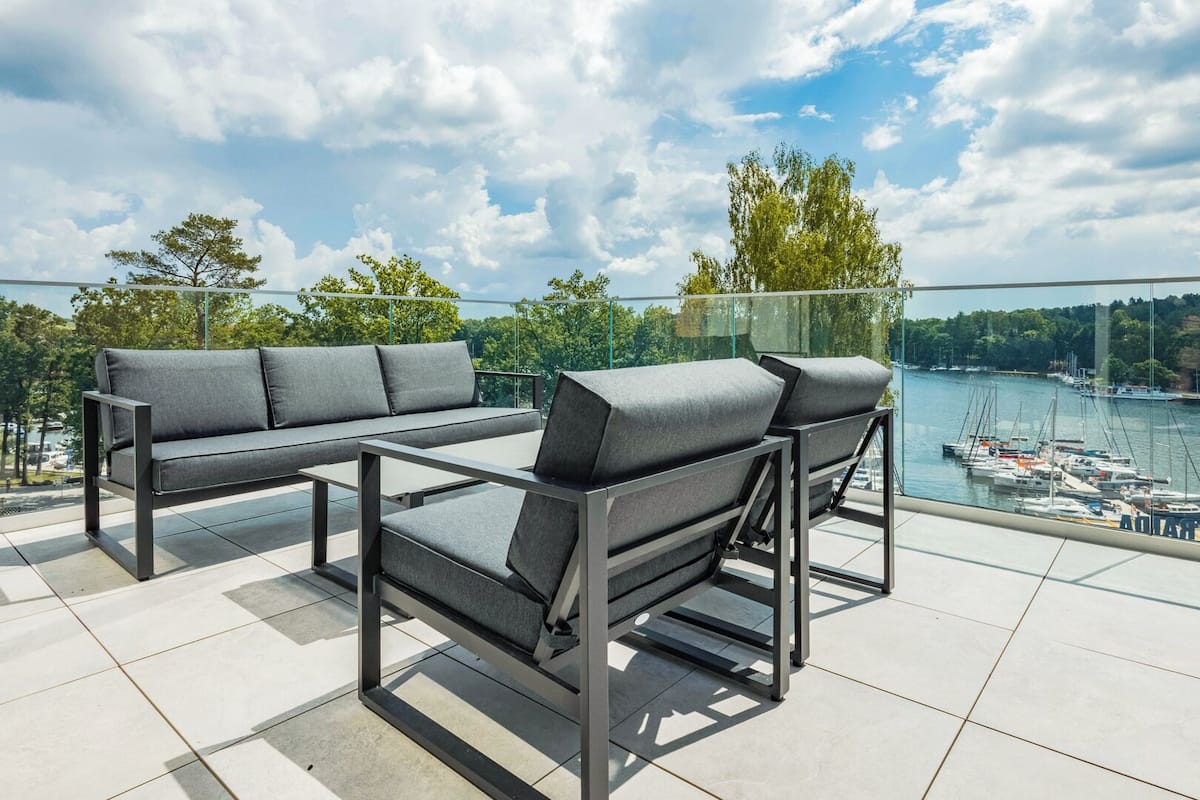 A balcony with a sofa and table, overlooking a body of water with boats.
