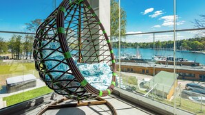 Una silla moderna con diseño geométrico, vista a un puerto deportivo con barcos y cielo despejado.