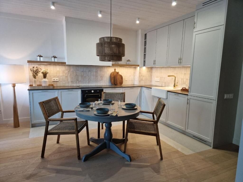 Una cocina moderna con una mesa redonda de comedor, dos sillas y una lámpara colgante.