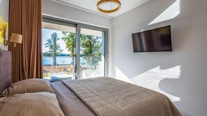 Una camera da letto con un letto grande, una TV a parete e una porta scorrevole in vetro che dà su un'area esterna.