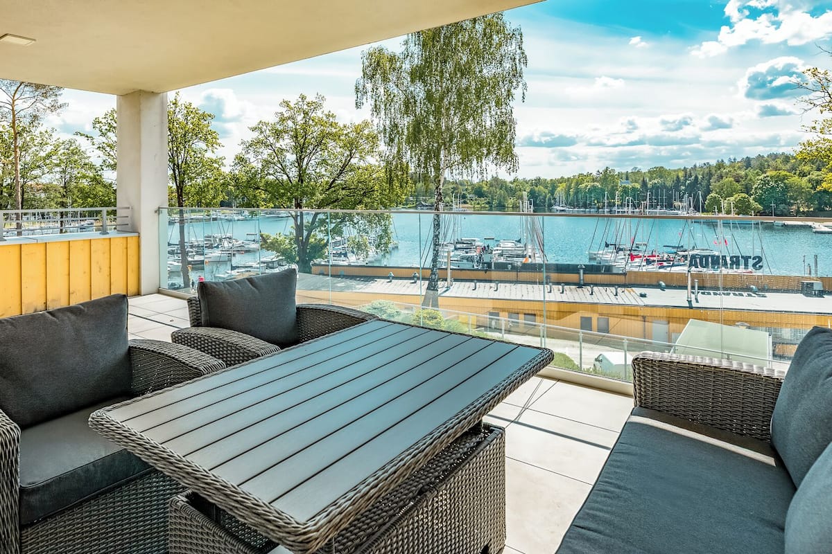 A balcony with wicker furniture, a view of a marina, and a yellow wall.