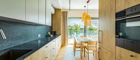 Una cocina moderna con armarios de madera, encimera negra y un comedor con mesa y sillas.