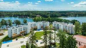 Un hotel de varios pisos con un patio central, piscina y vistas a un lago.