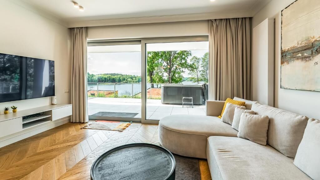 A modern living room with a large flat-screen TV, a sofa, a coffee table, and a sliding glass door leading to an outdoor area.